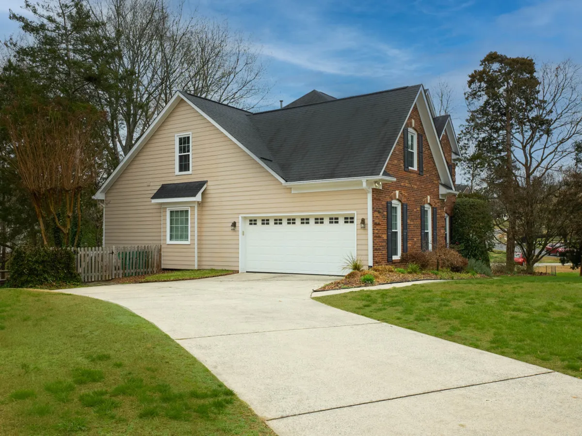 This image shows the front entrance of the home, complete with a well-maintained landscaped garden and a visible yard area. The focus on the entrance and surrounding greenery conveys a sense of welcome and hints at ample outdoor space for families and pets to enjoy.