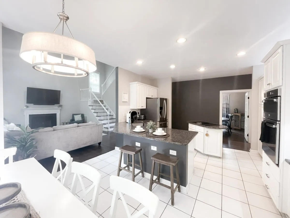 A welcoming open-plan interior showcasing a kitchen island, adjacent dining area, and a comfortable living room seating area. The seamless flow between spaces encourages easy socializing, shared meals, and effortless entertaining, enhanced by warm lighting and modern decor.