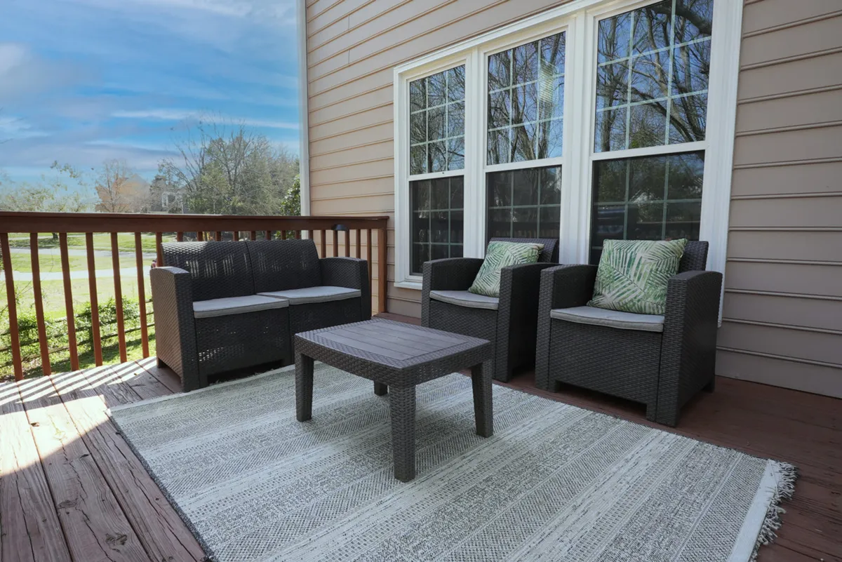 An inviting exterior seating area featuring a table and textured rug, surrounded by large windows that connect inside and out. The space exudes a comfortable, welcoming vibe—perfect for sunrise coffees, stargazing, or enjoying each other's company in a peaceful, wooded setting.