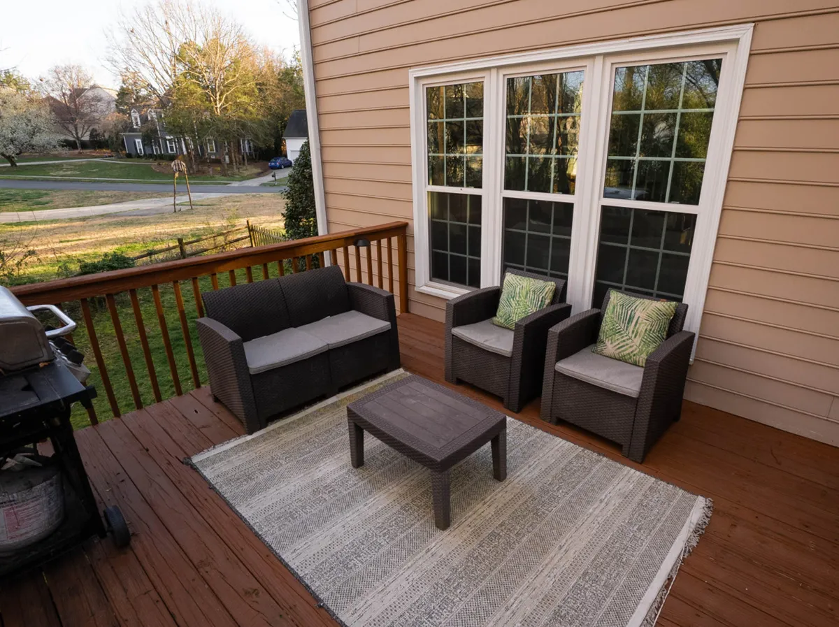 A welcoming outdoor seating area complete with a rug and grill, ideal for entertaining or unwinding. The setting showcases a relaxed ambiance, with comfortable furniture and gentle natural light, suggesting a peaceful retreat where guests can dine or relax together outdoors.