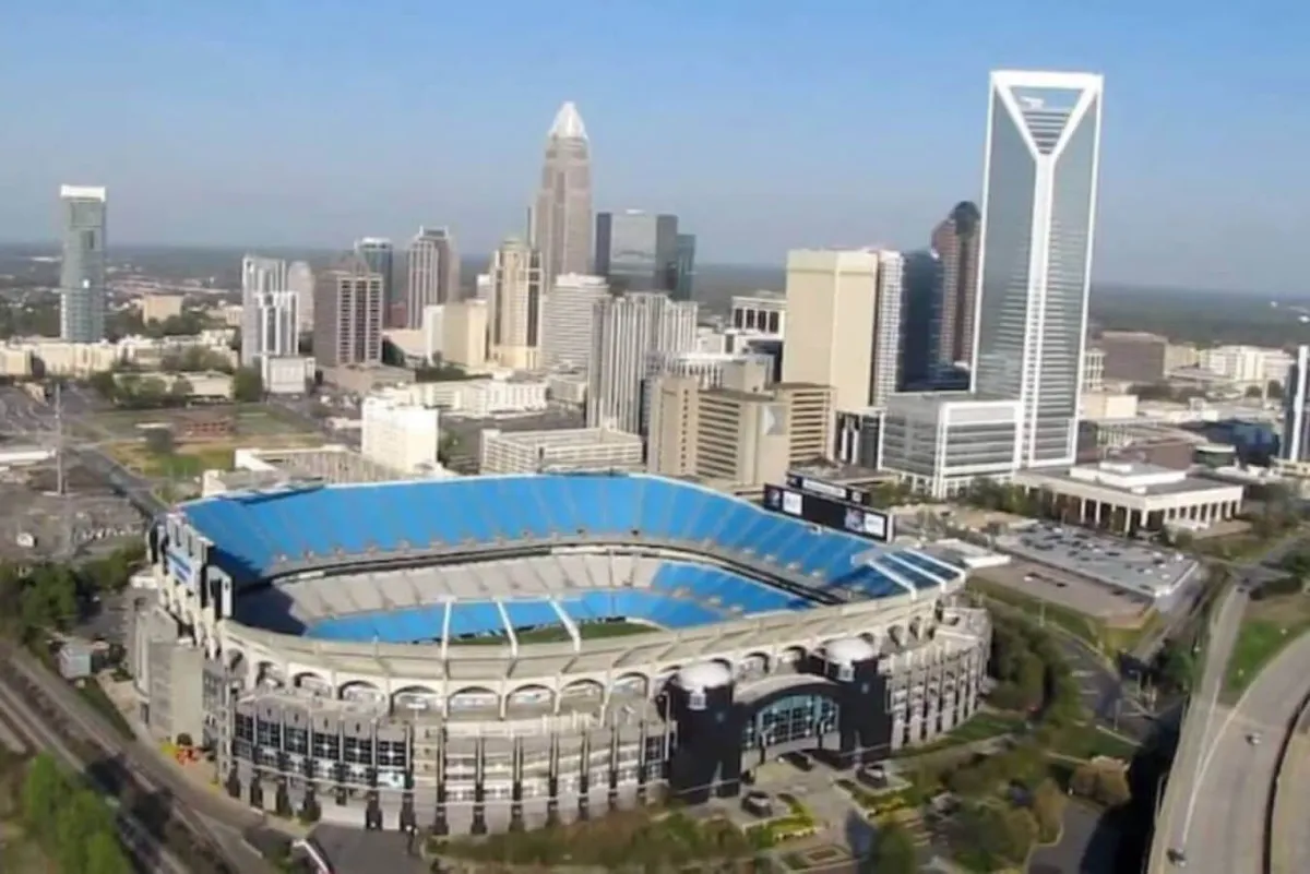 A vibrant cityscape featuring the Charlotte skyline, Bank of America Stadium, and surrounding green spaces. The image suggests easy access to urban activities, sports events, and city exploration from the property's location.